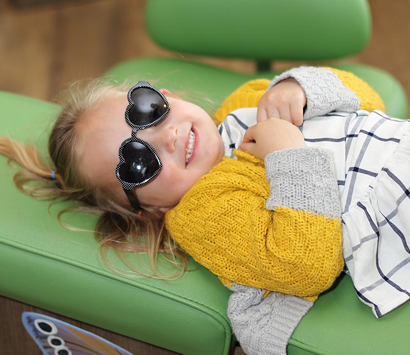 child laying on dentist chair smiling